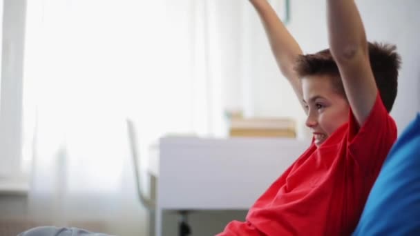 Niño feliz con gamepad jugando videojuego en casa — Vídeo de stock