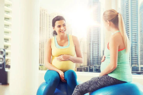 Duas mulheres grávidas felizes sentadas em bolas no ginásio — Fotografia de Stock
