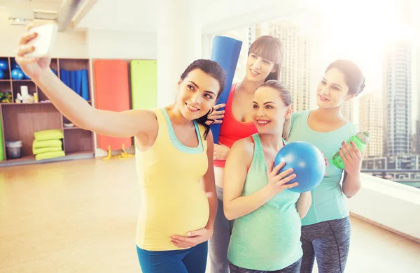 Mujeres embarazadas tomando selfie por teléfono inteligente en el gimnasio —  Fotos de Stock