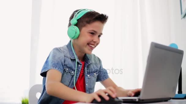 Niño en auriculares jugando videojuego en el ordenador portátil — Vídeos de Stock