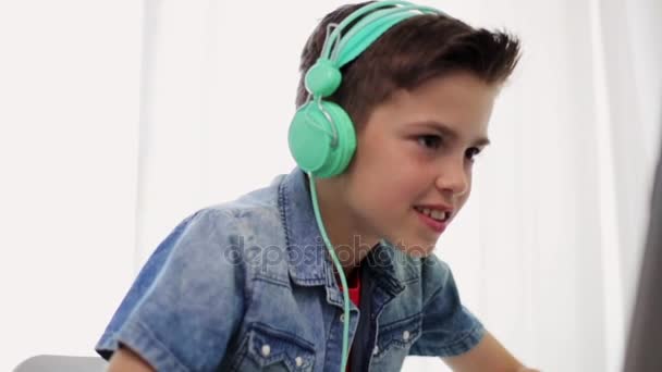 Мальчик в наушниках играет в видеоигры на ноутбуке — стоковое видео