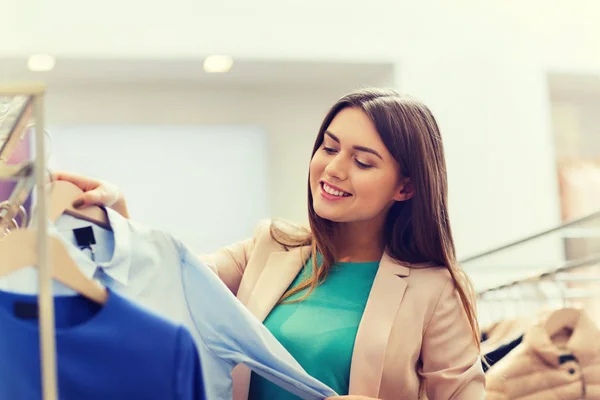 Happy young woman choosing clothes in mall — Stock Photo, Image