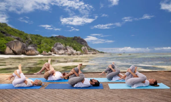 Grupp av människor att göra yogaövningar över stranden — Stockfoto