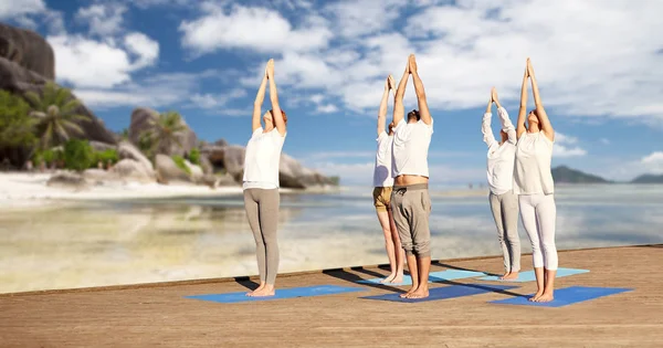 Grupp av människor att göra yogaövningar över stranden — Stockfoto