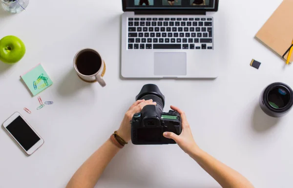 Mani di donna con macchina fotografica che lavora su computer portatile a tavola — Foto Stock