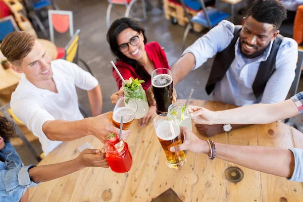 Vrienden rammelende bril met drankjes bij restaurant — Stockfoto