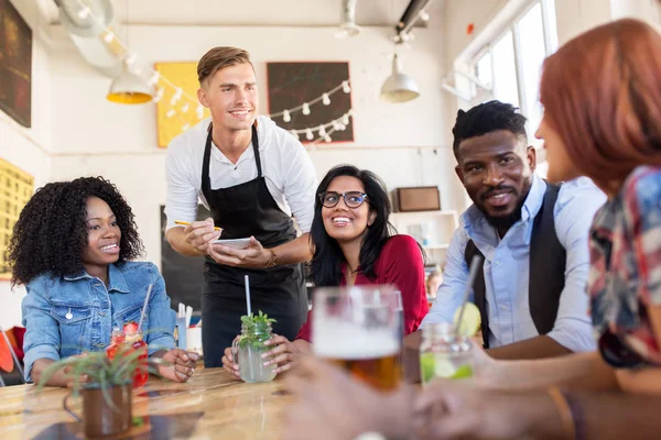 Kelner i przyjaciele z menu i napoje w barze — Zdjęcie stockowe