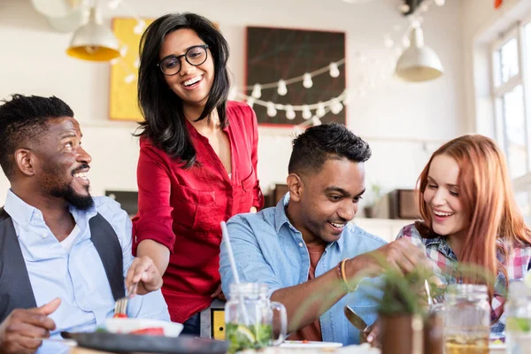 Happy friends eating at restaurant — Stock Photo, Image