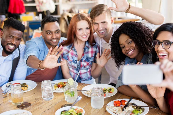 Amigos comendo e tomando selfie no restaurante — Fotografia de Stock