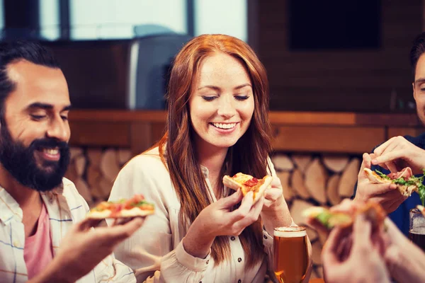 Vrienden eten pizza met bier in restaurant — Stockfoto