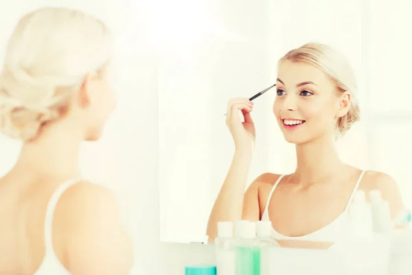 Mujer con cepillo haciendo maquillaje de cejas en el baño — Foto de Stock