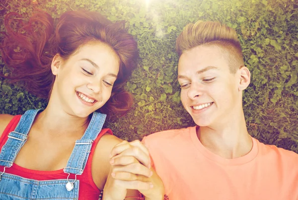 Happy teenage couple lying on grass at summer — Stock Photo, Image