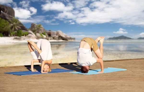 Tropikal plaj arka plan üzerinde yoga yaparken çift — Stok fotoğraf