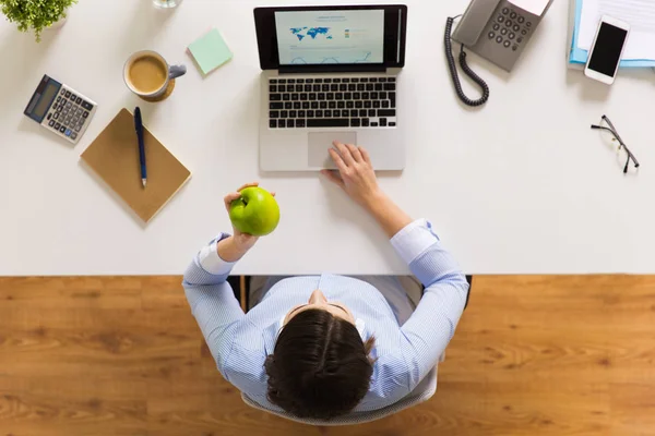 Empresaria con manzana y portátil en la oficina — Foto de Stock