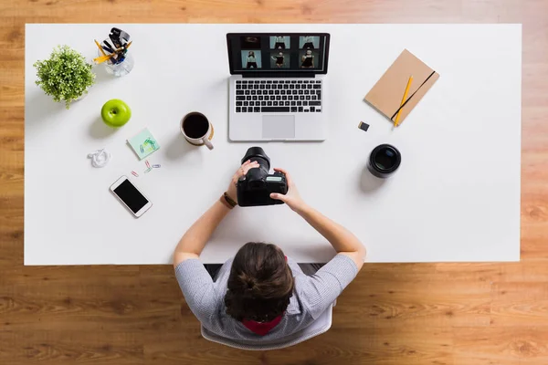 Женщина с камерой и ноутбуком за столом в офисе — стоковое фото