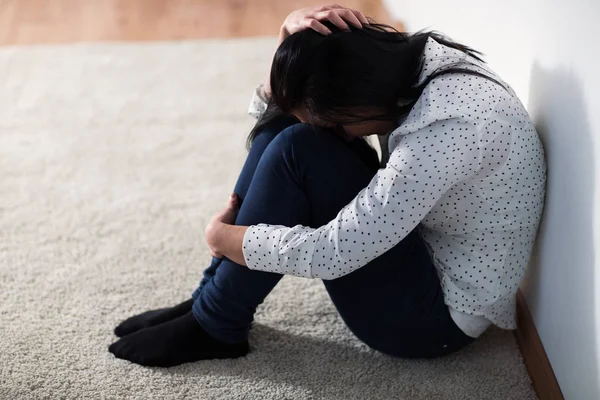 Mujer infeliz llorando en el suelo en casa —  Fotos de Stock