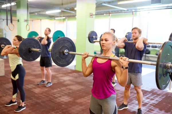 Gruppo di persone che si allenano con i bilancieri in palestra — Foto Stock