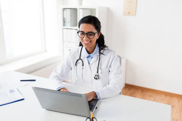 Mujer feliz médico escribiendo en el ordenador portátil en el hospital —  Fotos de Stock