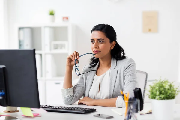 Geschäftsfrau mit Brille und Computer im Büro lizenzfreie Stockbilder