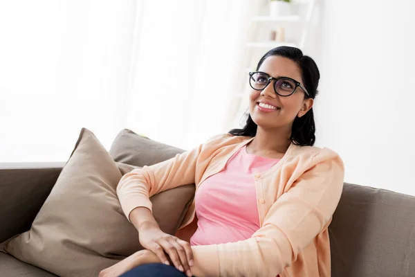 Щаслива усміхнена молода жінка сидить на дивані вдома Стокове Фото