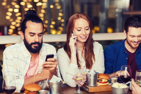 Glückliche Freunde mit Smartphones im Restaurant — Stockfoto