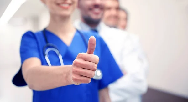 Close up of doctors at hospital showing thumbs — Stock Photo, Image