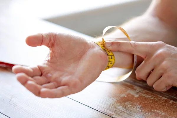 Gros plan des mains masculines avec ruban à mesurer poignet — Photo