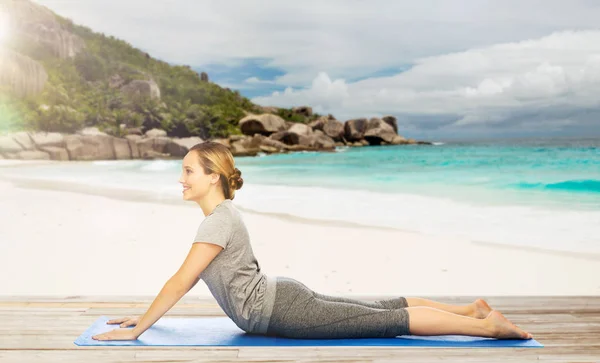 Kvinnan gör yoga i hund pose på stranden — Stockfoto