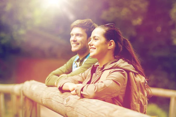 Sorrindo casal com mochilas na ponte na natureza — Fotografia de Stock