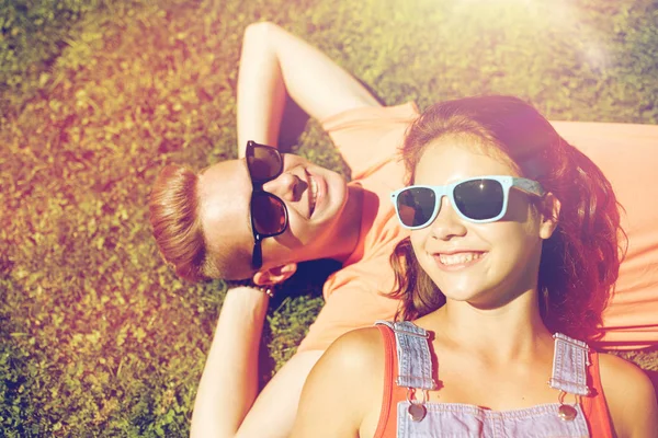 Happy teenage couple lying on grass at summer — Stock Photo, Image