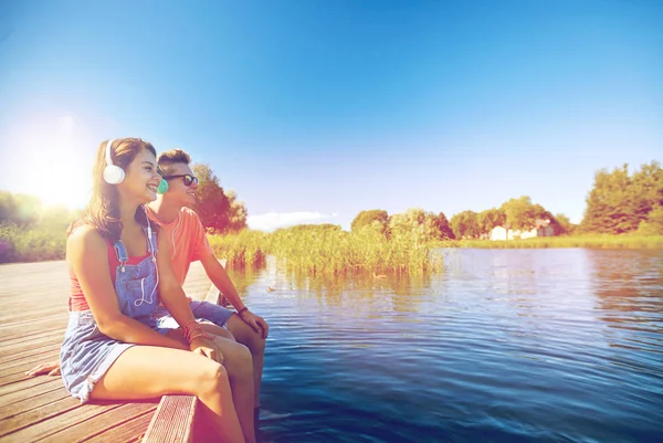 Szczęśliwa para nastolatków z słuchawki na nabrzeżu rzeki — Zdjęcie stockowe