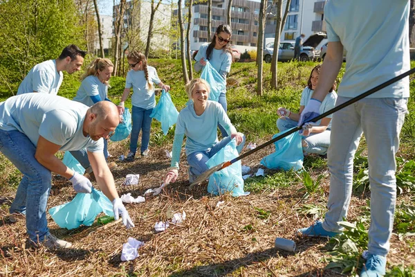 Voluntários com sacos de lixo área do parque de limpeza — Fotografia de Stock