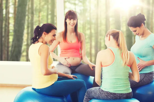 Mutlu hamile kadınlar spor salonunda topların üzerinde otururlar. — Stok fotoğraf