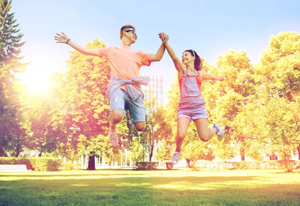 Feliz pareja adolescente saltando en el parque de verano —  Fotos de Stock