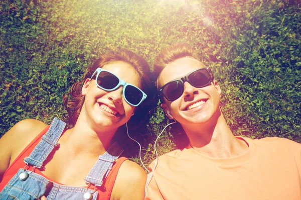 Счастливая пара подростков с наушниками, лежащими на траве — стоковое фото