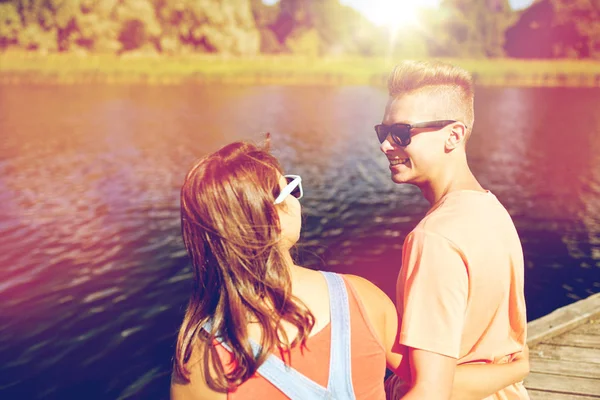 Šťastný dospívající pár sedí na řece kotviště — Stock fotografie