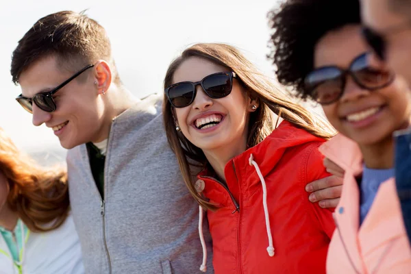 Happy teenage friends in shades talking on street — Stock Photo, Image