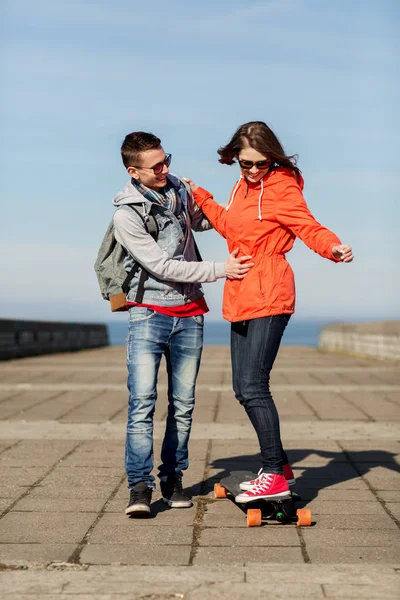 Happy couple with longboard riding outdoors — Stock Photo, Image