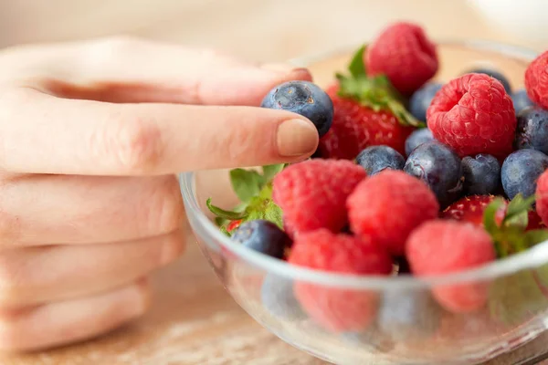 Крупним планом молода жінка рука з ягодами в мисці — стокове фото