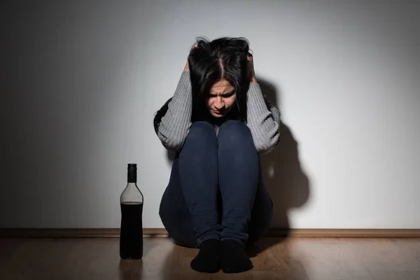 Mulher com garrafa de álcool chorando em casa — Fotografia de Stock