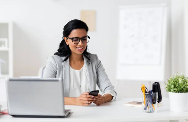 Mujer de negocios con smartphone y portátil en la oficina — Foto de Stock