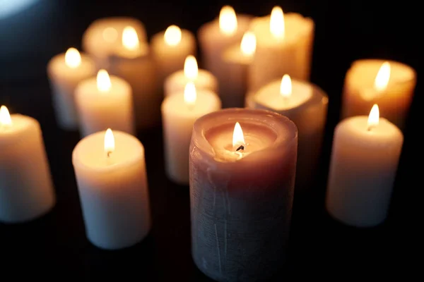 Kerzen brennen in der Dunkelheit vor schwarzem Hintergrund — Stockfoto