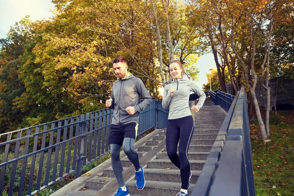 Happy couple running downstairs in city — Stock Photo, Image