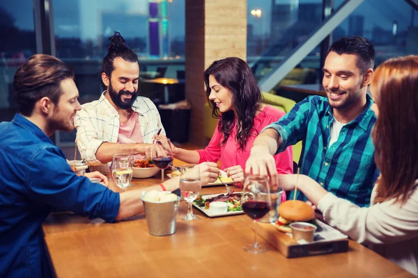 Amigos comer e degustação de alimentos no restaurante — Fotografia de Stock