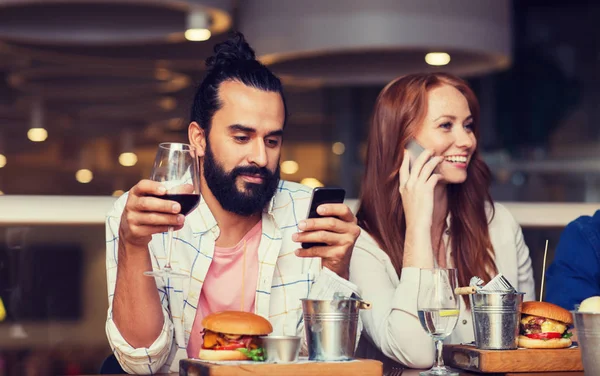 Щасливі друзі зі смартфонами в ресторані — стокове фото