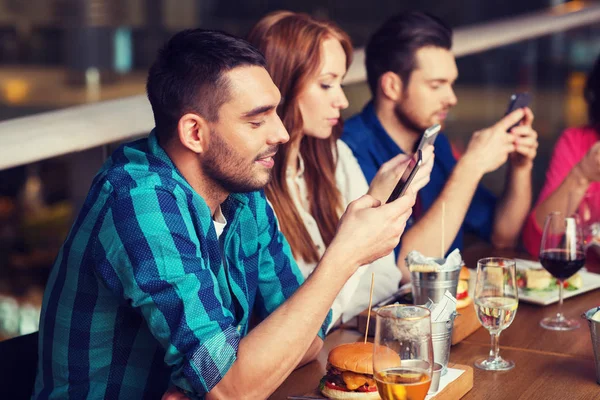 Friends with smartphones dining at restaurant — Stock Photo, Image