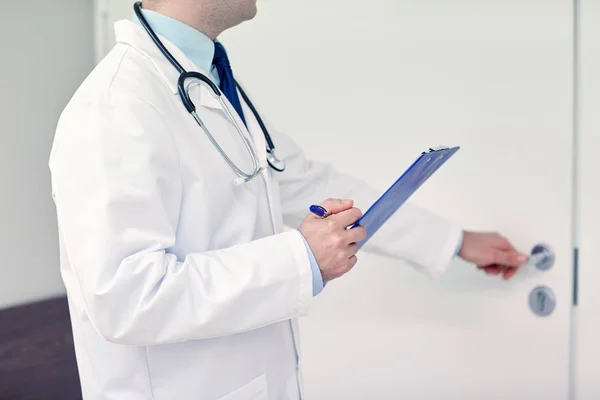 Close up of doctor with clipboard at hospital door — Stock Photo, Image