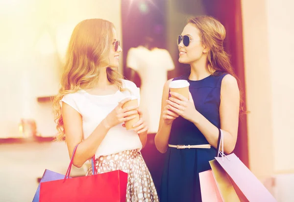 Jonge vrouwen met boodschappentassen en koffie bij shop — Stockfoto