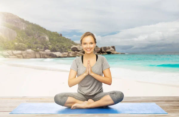 Женщина делает йогу медитации в позе лотоса на пляже — стоковое фото