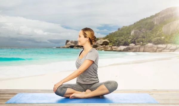 Mujer haciendo yoga en pose de giro en la playa —  Fotos de Stock